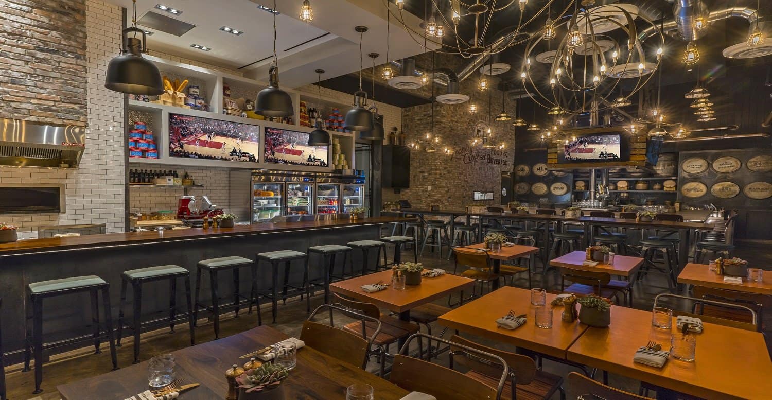 Hotel bar with tables for dining and multiple television displays showing a basketball game.