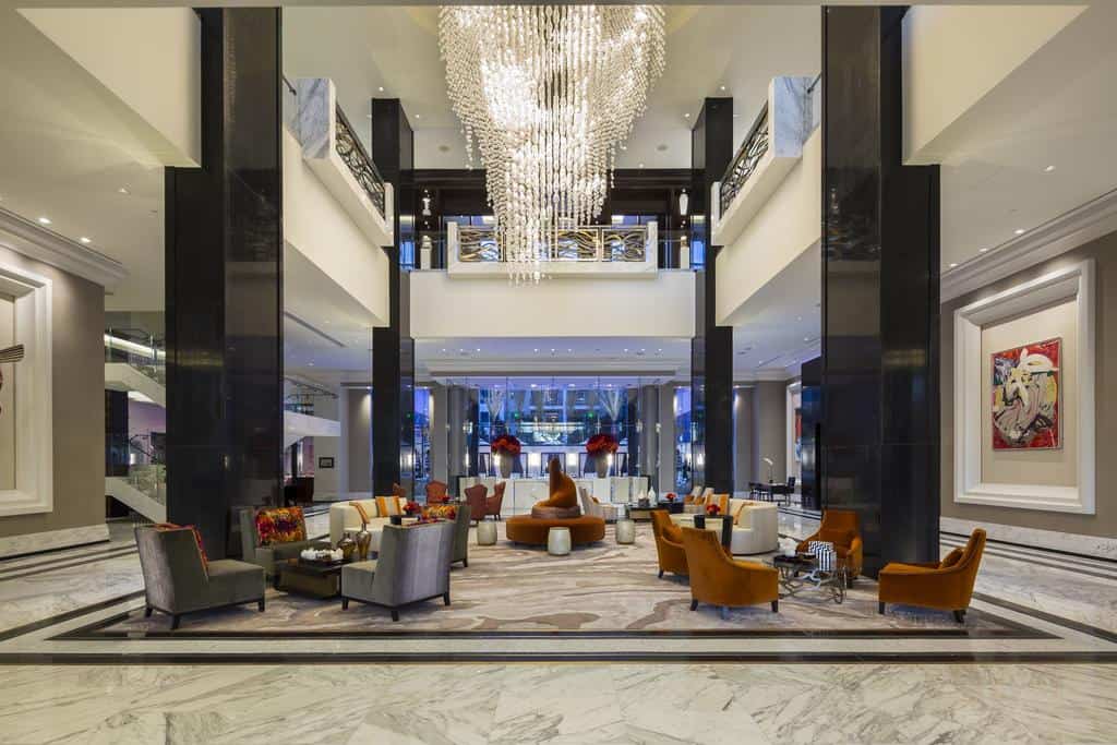 Lobby in a luxury hotel, featuring modern seating areas and modern art on the walls with a marble tile floor.