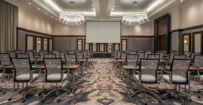 Hotel ball room turned into a conference room with stage, seating, and large projection screen.