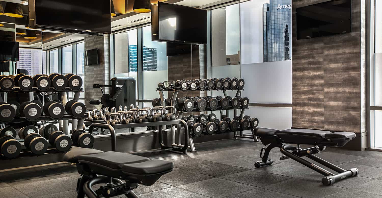 Racks of weights and weight benches in the Post Oak Hotel fitness center.