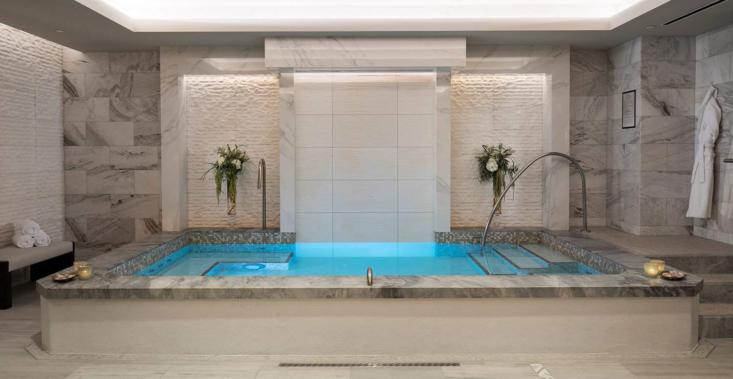 Hot tub in a hotel spa with candles and towels around the rim.