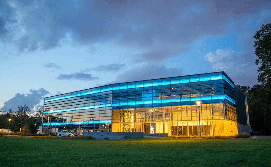 The exterior of a smart building with neon lighting at dusk.