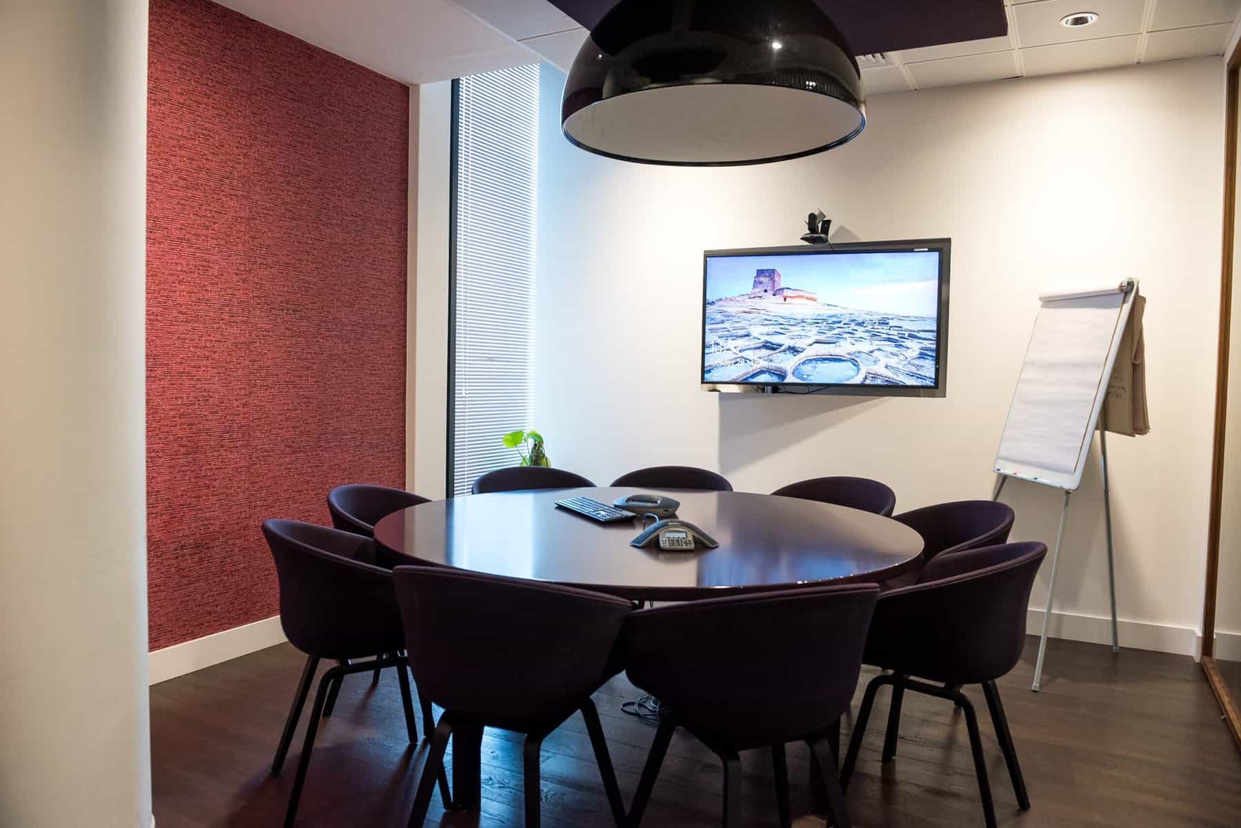 A small 10 person conference room with a webcam mounted above a television.