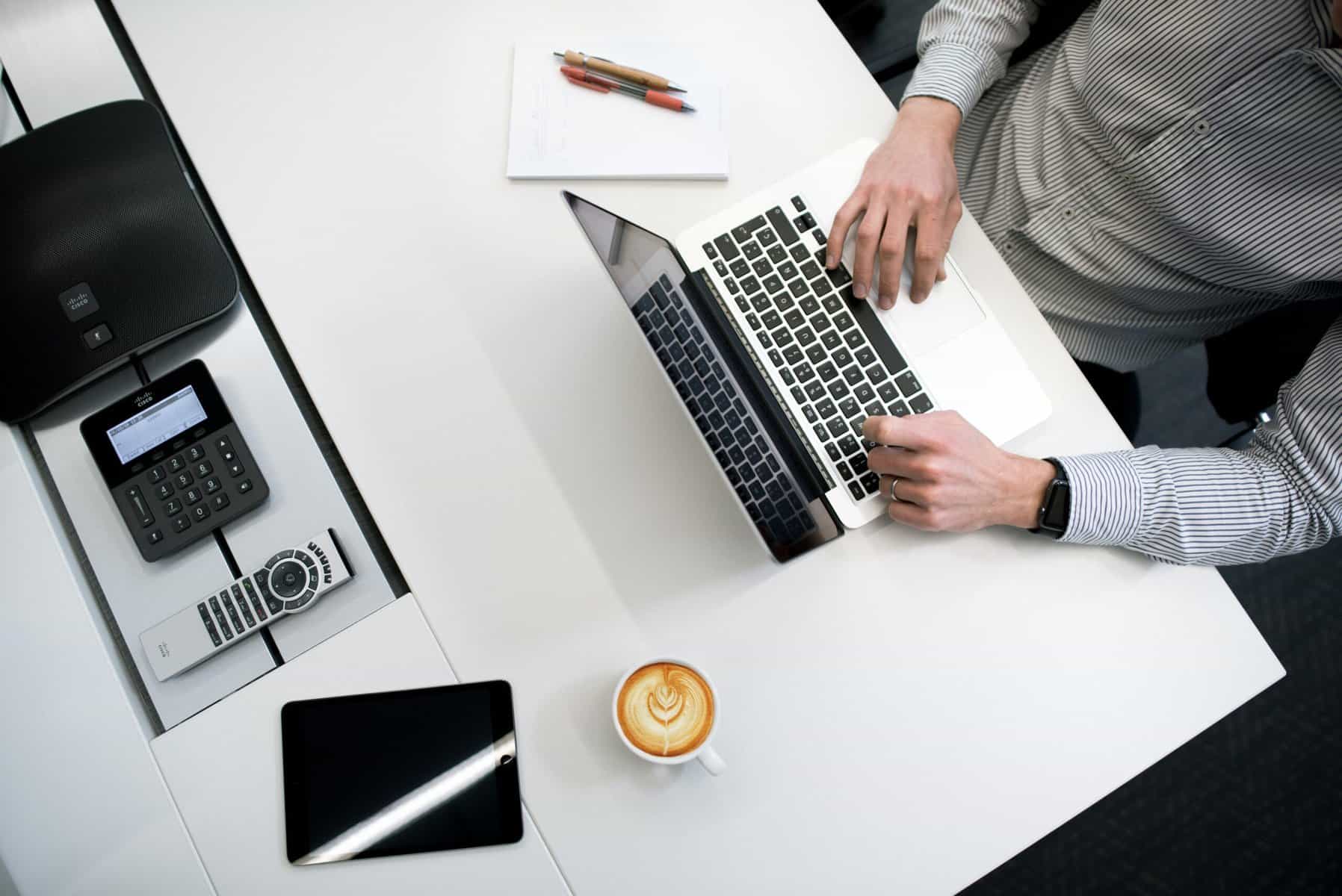 Employee at a desk with several smart devices.