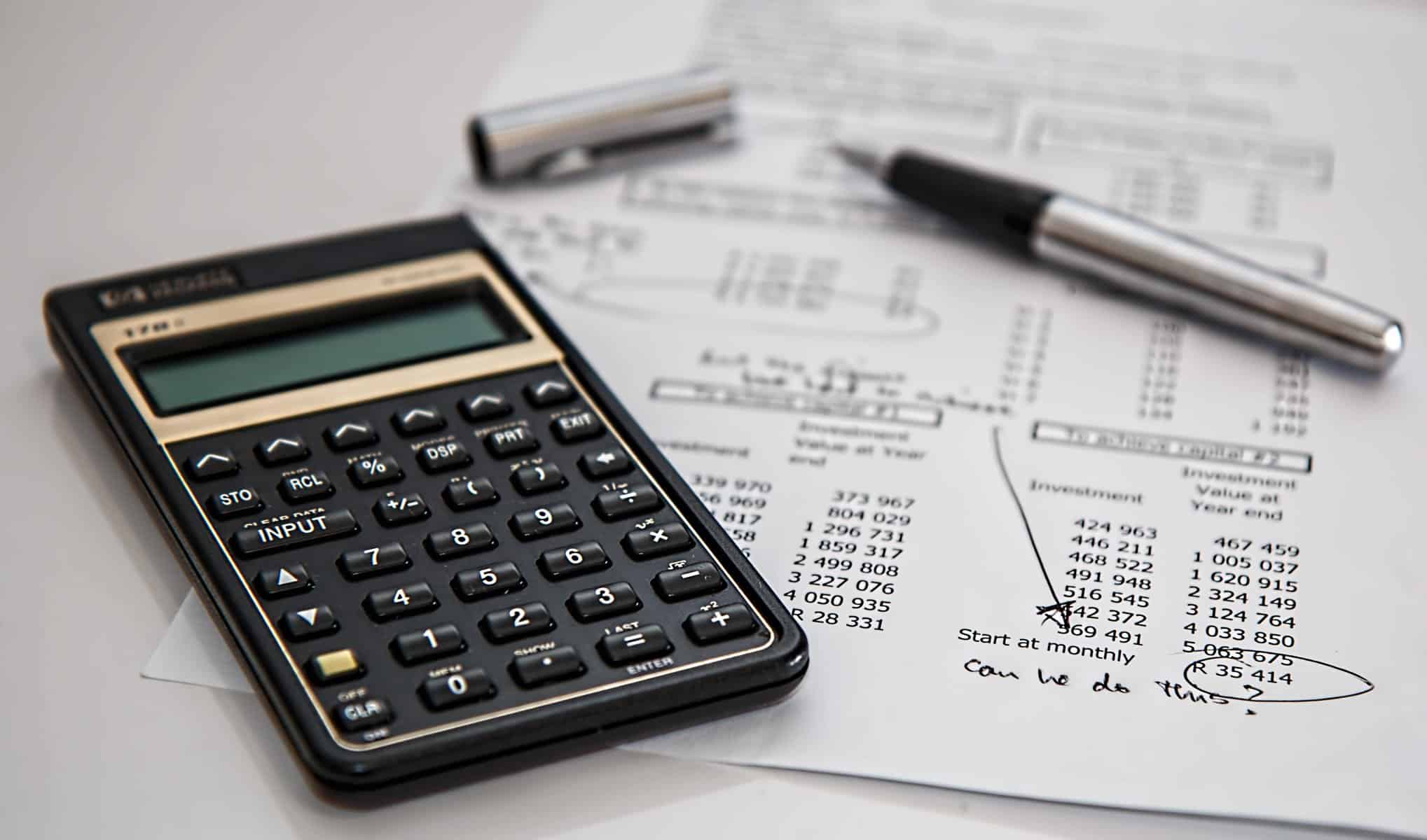 A calculator and an IT budget sitting on a white desk