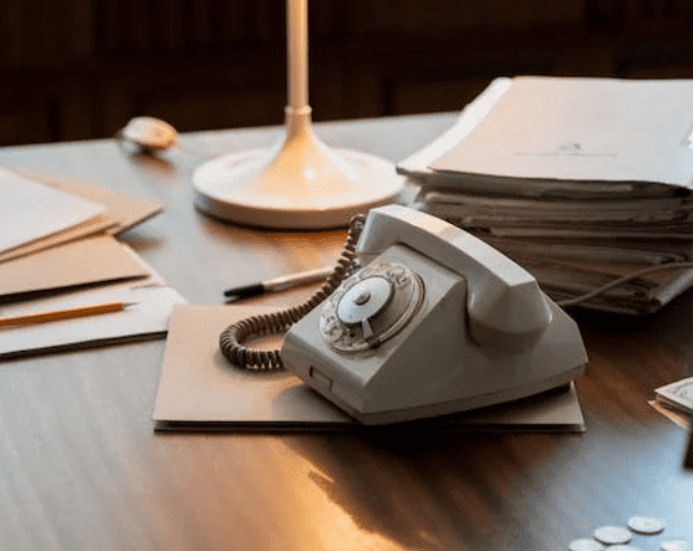 Old telephone sitting on an office desk.